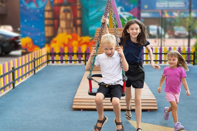 Giro con l'elastico per bambini Giro in corda con l'altalena in un moderno parco giochi Aiuto reciproco di amici