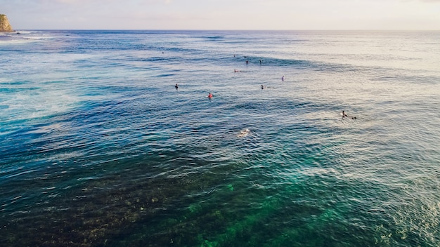 Giro del surfista sulle onde nel tramonto dell'oceano, vista dall'alto