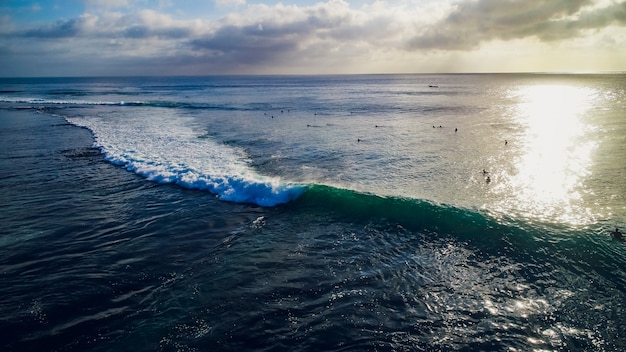 Giro del surfista sulle onde nel tramonto dell'oceano, vista dall'alto