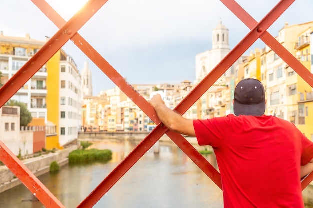 Girona città medievale, un giovane turista che guarda la città dal famoso ponte rosso Pont de les Peixateries Velles, Costa Brava della Catalogna