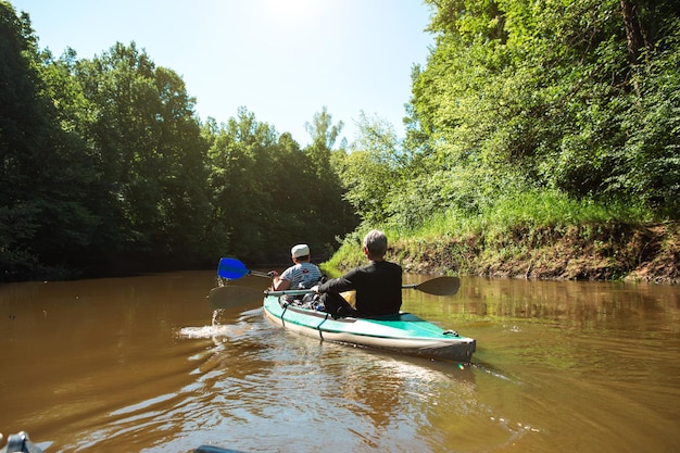 Gita in kayak in famiglia Una coppia di anziani coniugi che rema su una barca sul fiume un'escursione in acqua un'avventura estiva Sport legati all'età gioventù mentale e turismo della salute vecchiaia attiva