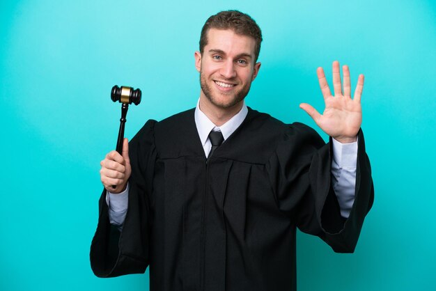 Giudice uomo caucasico isolato su sfondo blu salutando con la mano con espressione felice