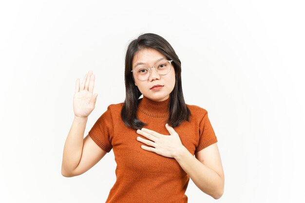 Giuramento o gesto di promessa di bella donna asiatica isolata su sfondo bianco