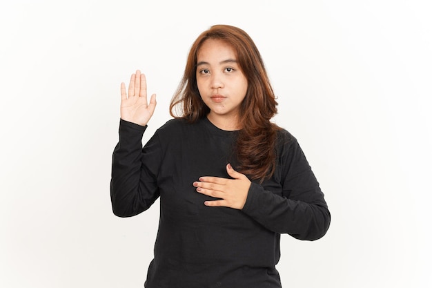 Giuramento o gesto di promessa di una bella donna asiatica che indossa una camicia nera isolata su bianco