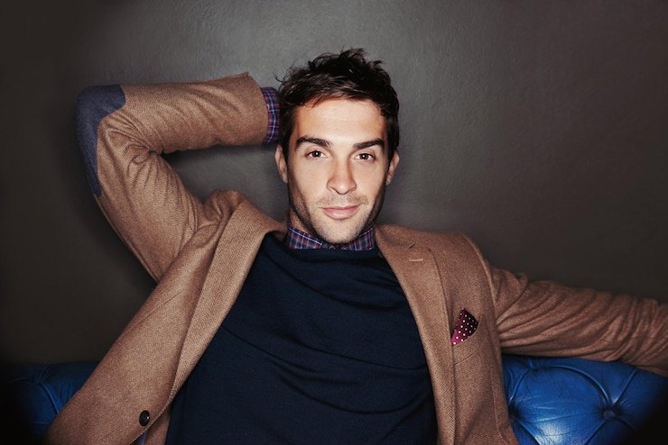 Foto glamour di moda e ritratto di un uomo sul divano con fiducia abbigliamento di designer e cultura di lusso rilassarsi gentiluomo e modello maschile con stile alla moda seduto su un divano di pelle con sfondo scuro