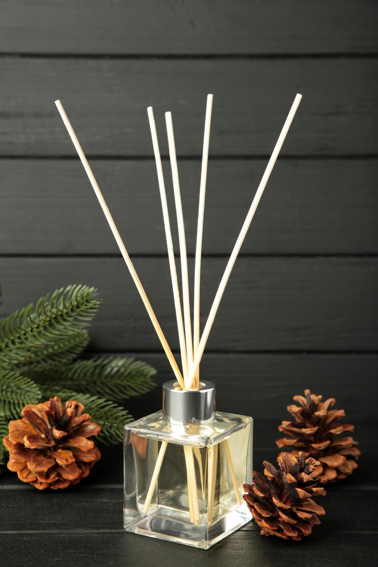 Glass bottle of aroma diffuser and pine cones on black wooden background Vertical photo