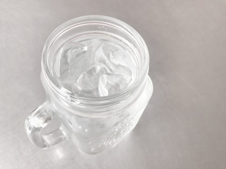 Glass of cool water with cube ice on gray table