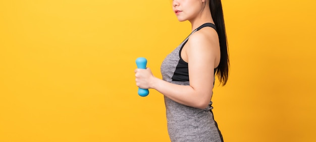 Gli abiti sportivi d'uso della donna asiatica di smiley che pompano i muscoli con la testa di legno blu su arancione-chiaro.