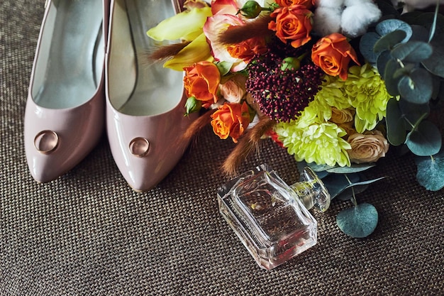 Gli accessori da sposa come l'anello del bouquet di scarpe e il profumo giacciono su un tavolo