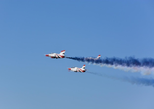 Gli aerei da combattimento militari volano in gruppo con il fumo nel cielo blu