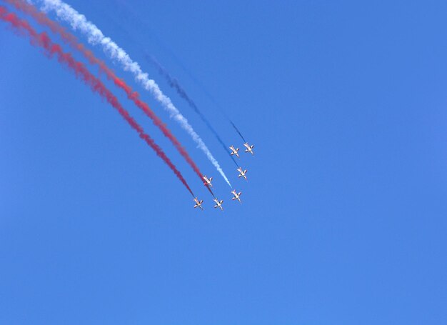 Gli aerei da combattimento militari volano in gruppo con il fumo nel cielo blu