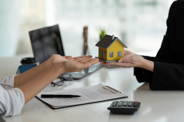 Gli agenti immobiliari accettano di acquistare una casa e di fornire un modello di casa ai clienti presso gli uffici della loro agenzia Accordo concettuale