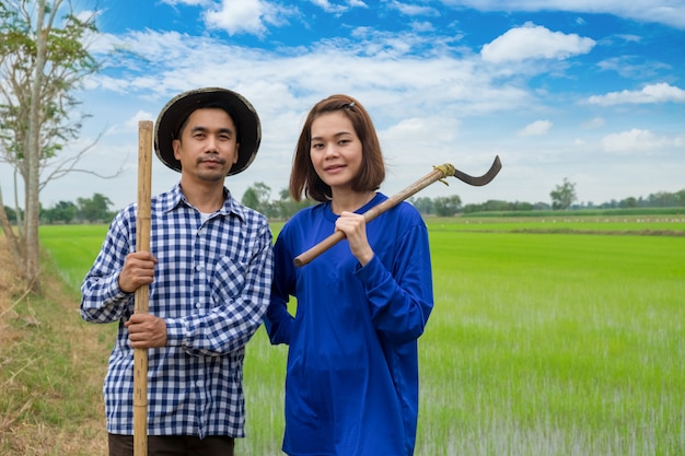 Gli agricoltori asiatici coppia gli strumenti di tenuta nell&#39;azienda agricola del riso alla Tailandia