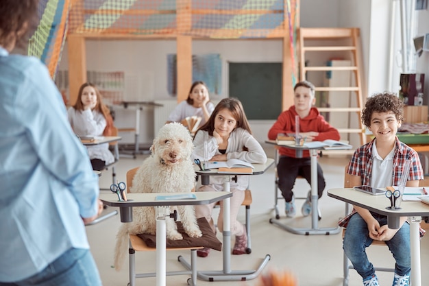Gli alunni a lezione di scuola elementare con un cane al centro