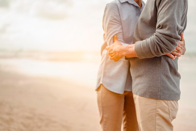 Gli amanti anziani si abbracciano e si baciano al tramonto sulla spiaggia Pianifica un'assicurazione sulla vita con un concetto di pensionamento felice.