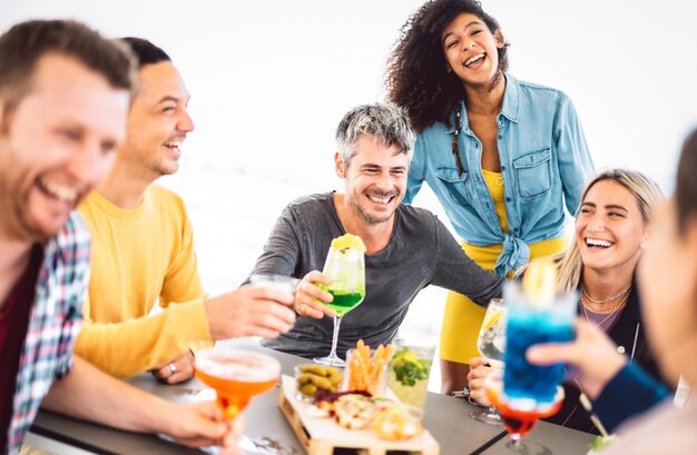 Gli amici brindano a fantasiose bevande colorate sulla terrazza del cocktail bar all'aperto