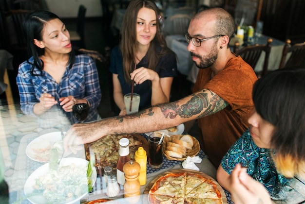 Gli amici che mangiano la pizza fanno festa insieme il concetto