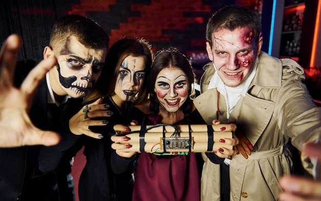 Gli amici con la bomba in mano sono alla festa di halloween a tema con trucco e costumi spaventosi.