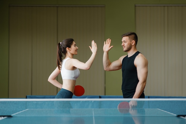 Gli amici con le racchette se ne danno cinque a vicenda prima del torneo di ping pong al chiuso.