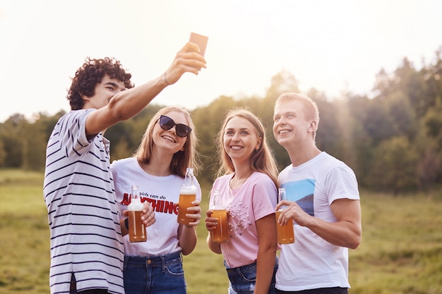 Gli amici felici bevono bevande energetiche, posano per selfie