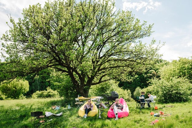 Gli amici fumano narghilè e si rilassano nella natura Genitori con bambini durante un picnic Vacanze per il tempo libero che mangiano persone e concetto di cibo amici felici alla festa estiva in giardino