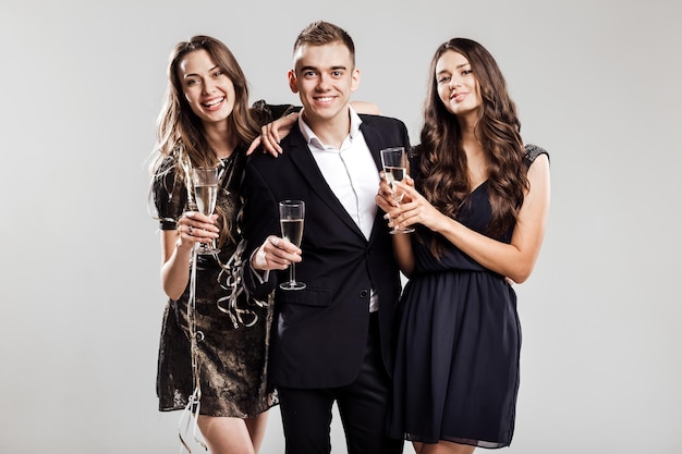 Gli amici in abiti eleganti e alla moda sorridono insieme tenendo in mano bicchieri di champagne
