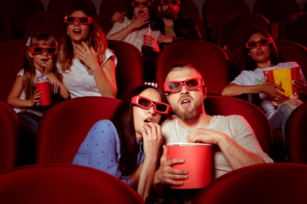 Gli amici seduti al cinema guardano film mangiando popcorn e acqua potabile.