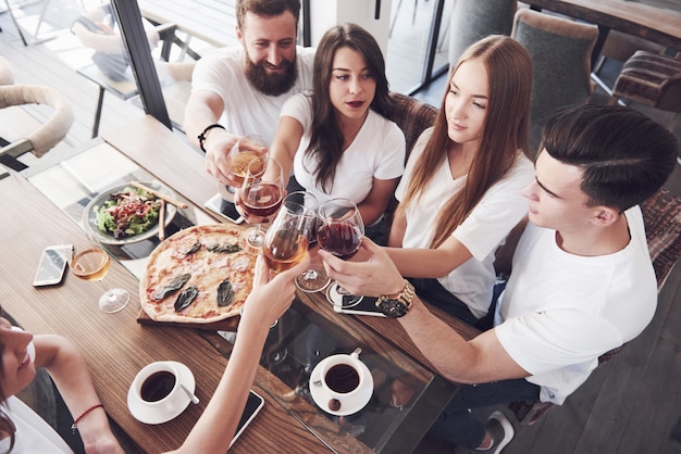 Gli amici si sono riuniti a tavola con cibo delizioso con bicchieri di vino rosso per festeggiare un'occasione speciale