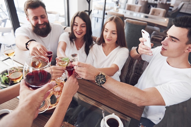 Gli amici si sono riuniti a tavola con cibo delizioso con bicchieri di vino rosso per festeggiare un'occasione speciale