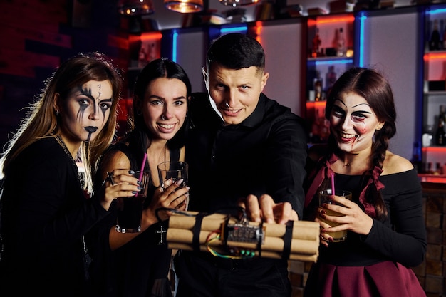 Gli amici sono alla festa tematica di Halloween con trucco e costumi spaventosi e bomba in mano.