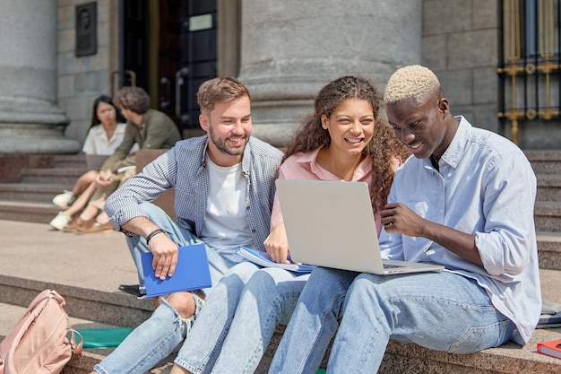 Gli amici sono studenti che usano un laptop mentre sono seduti sui gradini