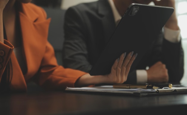Gli analisti finanziari analizzano i rapporti finanziari aziendali su un progetto di investimento di pianificazione di tablet digitali durante una discussione in una riunione aziendale che mostra i risultati del loro lavoro di squadra di successo