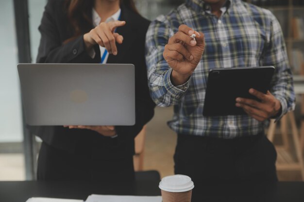 Gli analisti finanziari analizzano i rapporti finanziari aziendali su un tablet digitale pianificando un progetto di investimento durante una discussione in una riunione aziendale che mostra i risultati del loro lavoro di squadra di successo