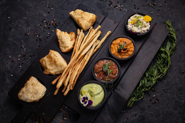 Gli antipasti, le salse con crostini di pane e bastoncini al forno vengono serviti su supporti di legno. Su cemento scuro