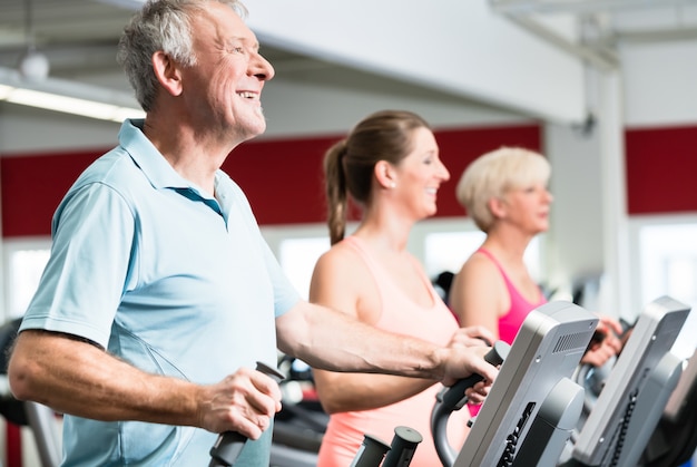 Gli anziani si allenano su cross trainer con personal trainer in palestra