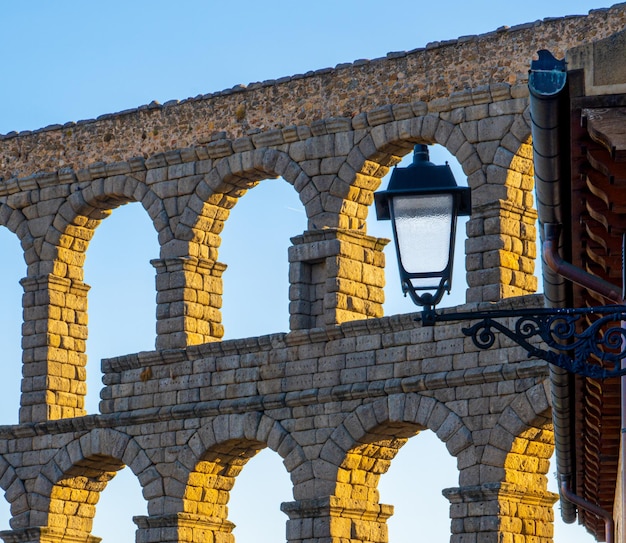 Gli archi dell'acquedotto di Segovia illuminati dalla luce del sole della sera Brillano i lampioni