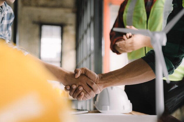 Gli architetti e gli ingegneri dei lavoratori edili si stringono la mano mentre lavorano per il lavoro di squadra e la cooperazione dopo aver completato un accordo in un concetto di cooperazione di successo della struttura dell'ufficio