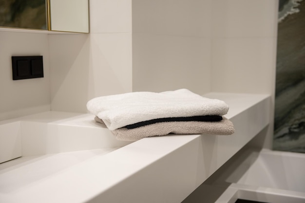 Gli asciugamani di spugna piegati giacciono su uno scaffale in bagno
