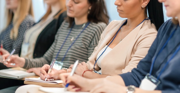 Gli ascoltatori prendono appunti sui quaderni, seduti nella sala conferenze