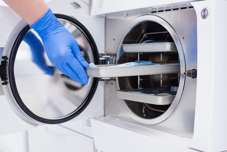 Gli assistenti consegnano i guanti inseriscono lo strumento dentale confezionato nell'autoclave per sterilizzarlo