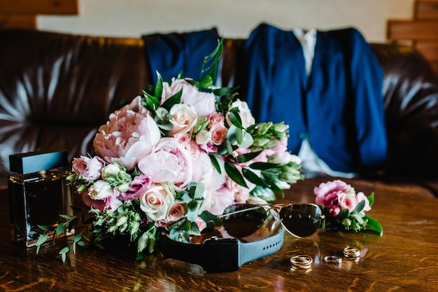 Gli eleganti occhiali da orologio da uomo si adattano a fiori e profumo per lo sposo Accessori per matrimoni su tavola marrone rustica Vista laterale