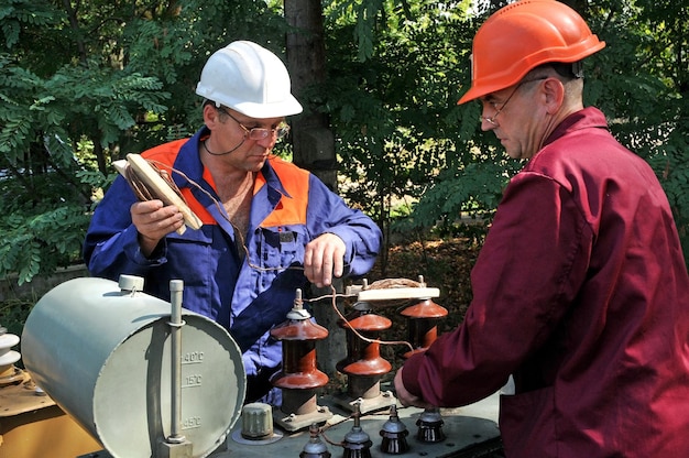 Gli elettricisti controllano la funzionalità degli isolatori sul trasformatore dell'olio durante la manutenzione