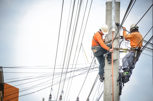 Gli elettricisti stanno salendo sui pali elettrici per installare e riparare le linee elettriche.