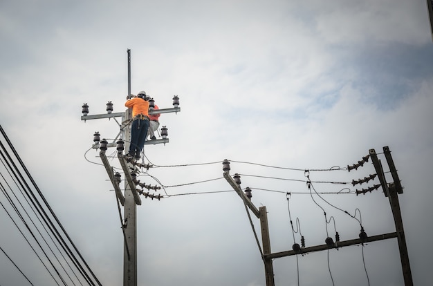 Gli elettricisti stanno salendo sui pali elettrici per installare e riparare le linee elettriche.