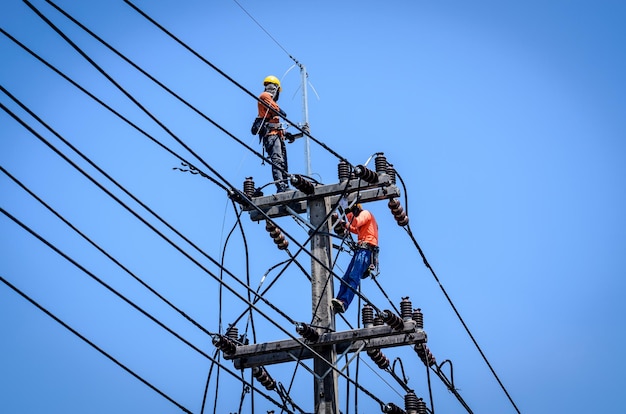 Gli elettricisti stanno salendo sui pali elettrici per installare e riparare le linee elettriche.