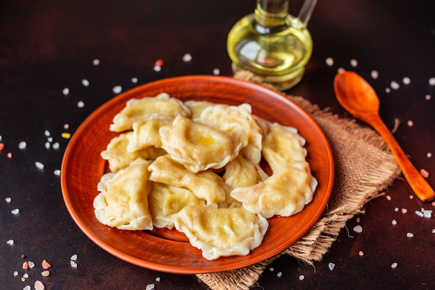 Gli gnocchi fatti bollire con un ripieno di olio e cipolle verdi su un tavolo scuro. Può essere usato come sfondo