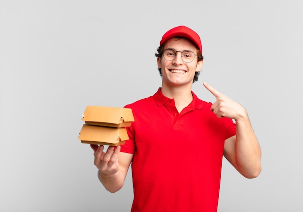 Gli hamburger consegnano un ragazzo sorridente che indica con sicurezza il proprio ampio sorriso, un atteggiamento positivo, rilassato e soddisfatto