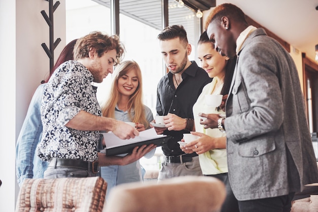 Gli imprenditori di successo utilizzano gadget, parlano e sorridono durante la pausa caffè in ufficio