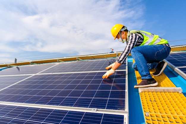 Gli ingegneri utilizzano un computer portatile per esaminare i pannelli solari in una centrale elettrica installata con pannelli solari che utilizzano l'energia solare.