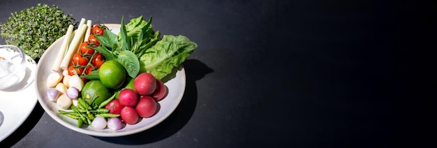 Gli ingredienti dell'insalata piccante sono preparati su un tavolo in granito nero con vari percorsi di ritaglio di verdure ed erbe